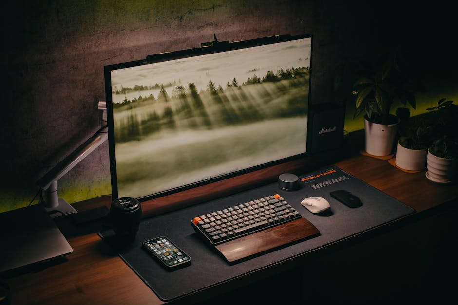Elegant computer setup featuring keyboard, monitor, and plants on a wooden desk.